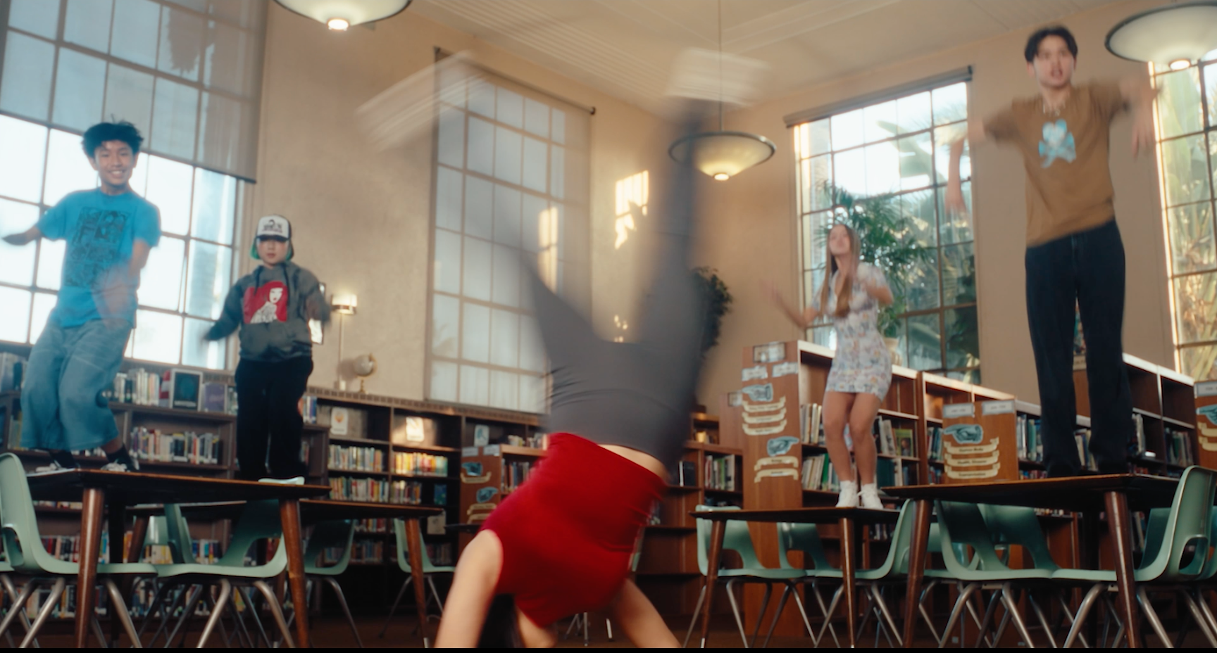 A girl in a pink tank top is dancing in front of a group of people.