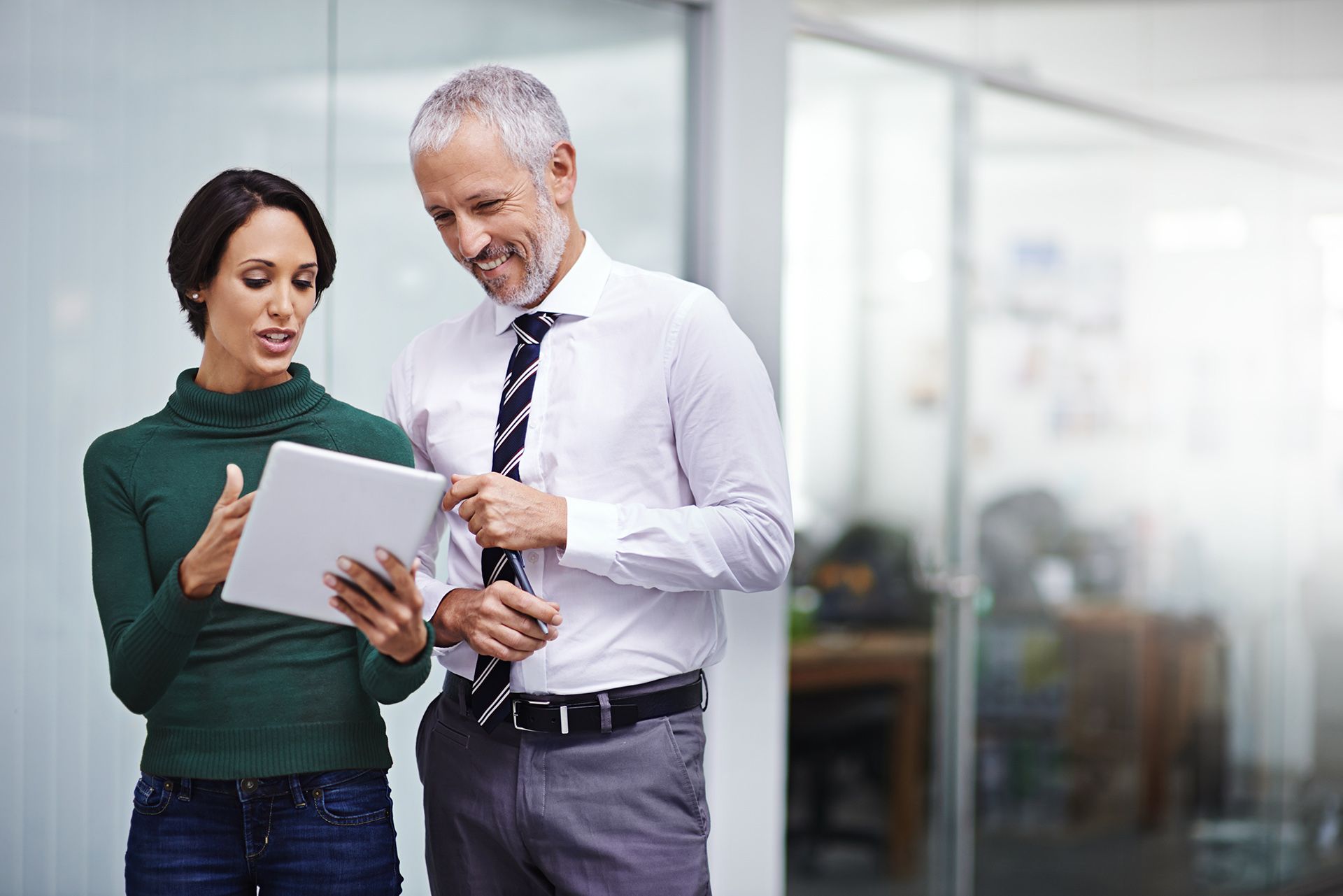 A man and a woman are looking at a tablet together.
