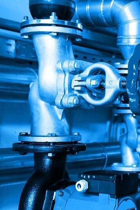 Tuberías y válvulas en una sala de máquinas, entorno industrial en tonos azules.