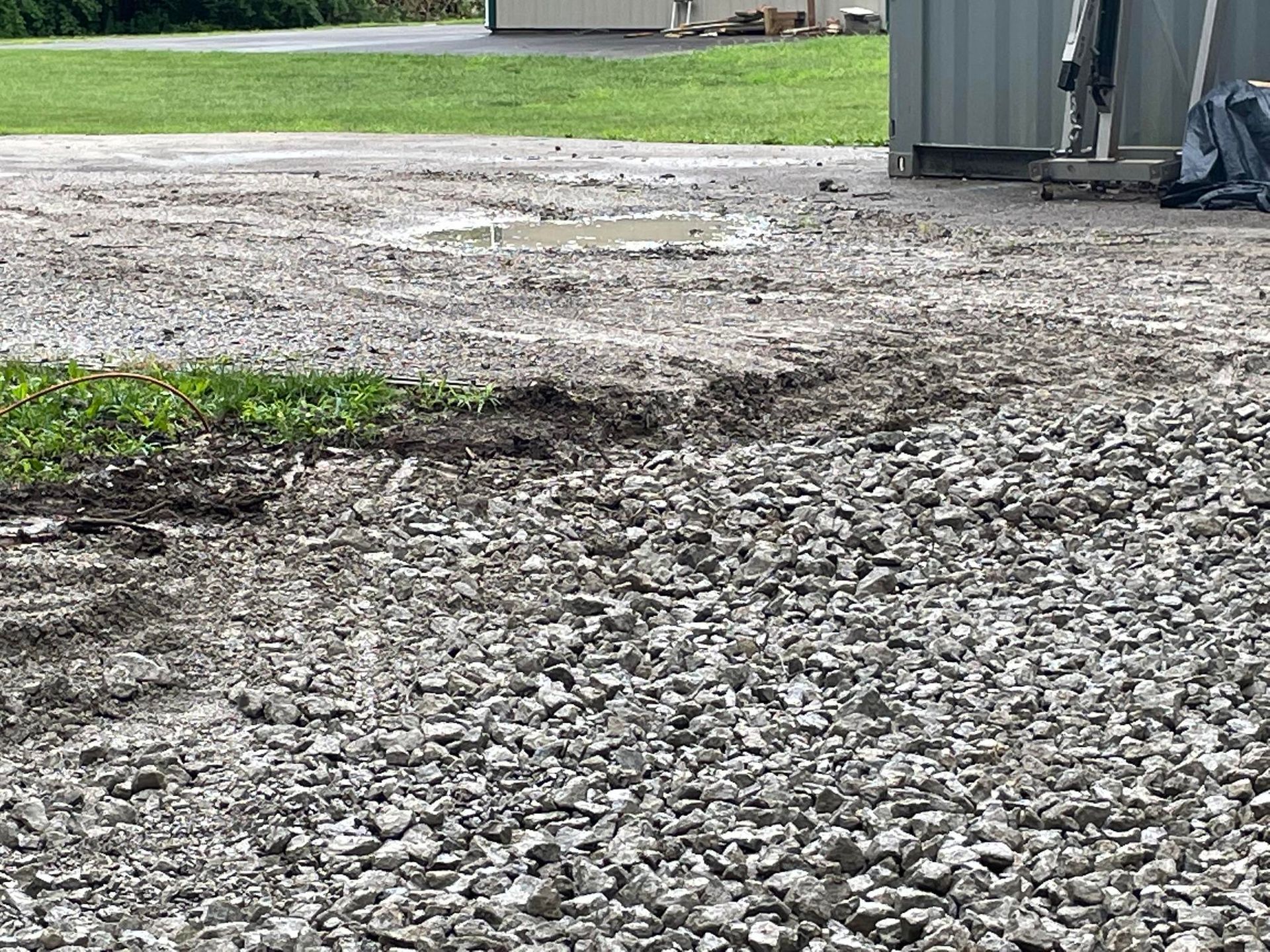 Gravel driveway beside a grassy yard, with a shed and driveway edge in view.