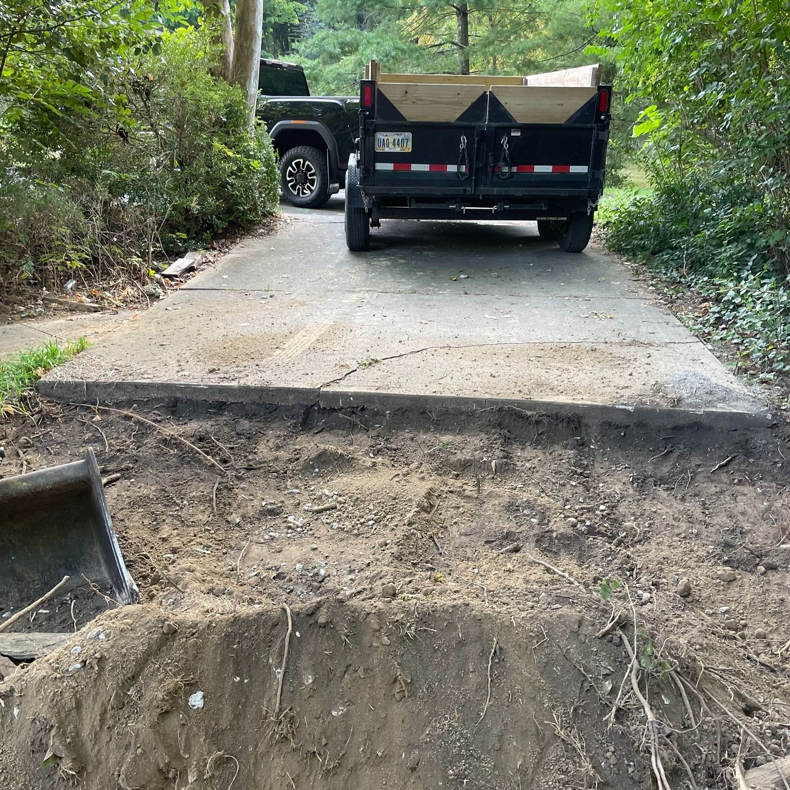 Pickup truck on a narrow dirt road with a washed-out section and exposed erosion ditch.