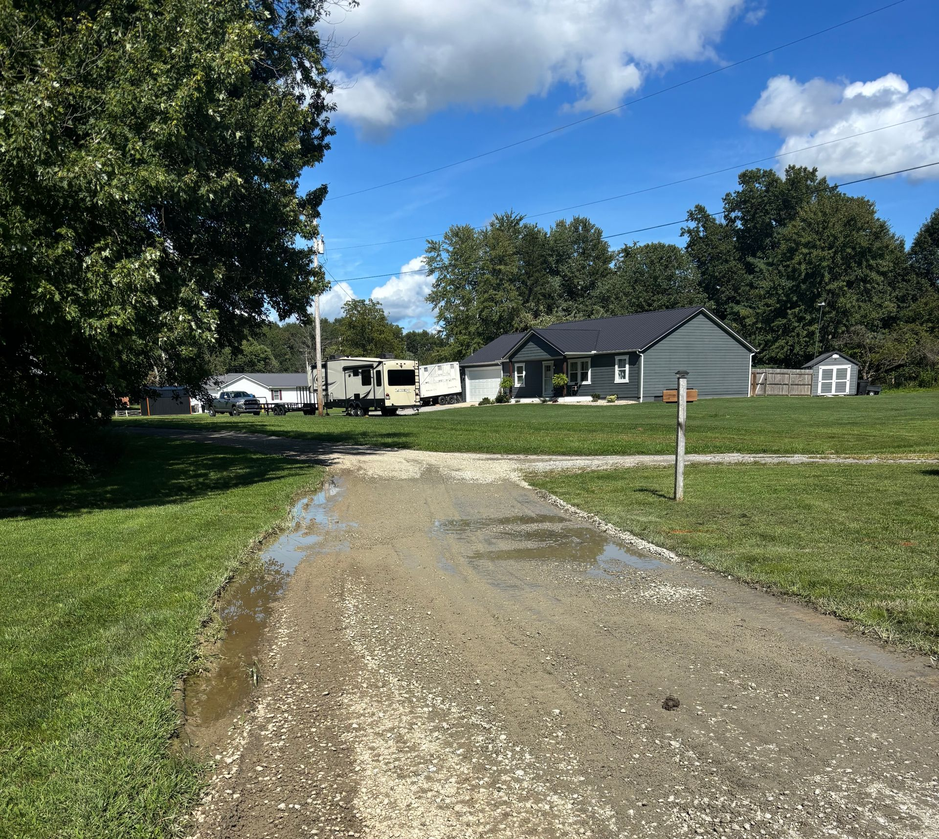 Gravel driveway in Winchester Ohio with potholes and standing water before repair.