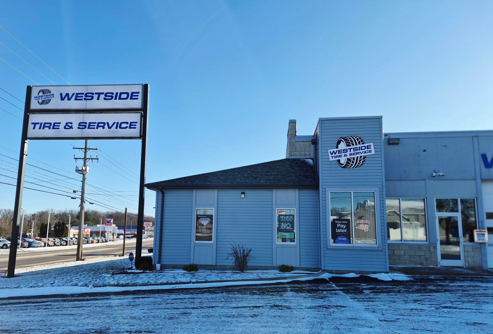 Store front on a snowy roadside under a clear blue sky | Westside Tire & Service