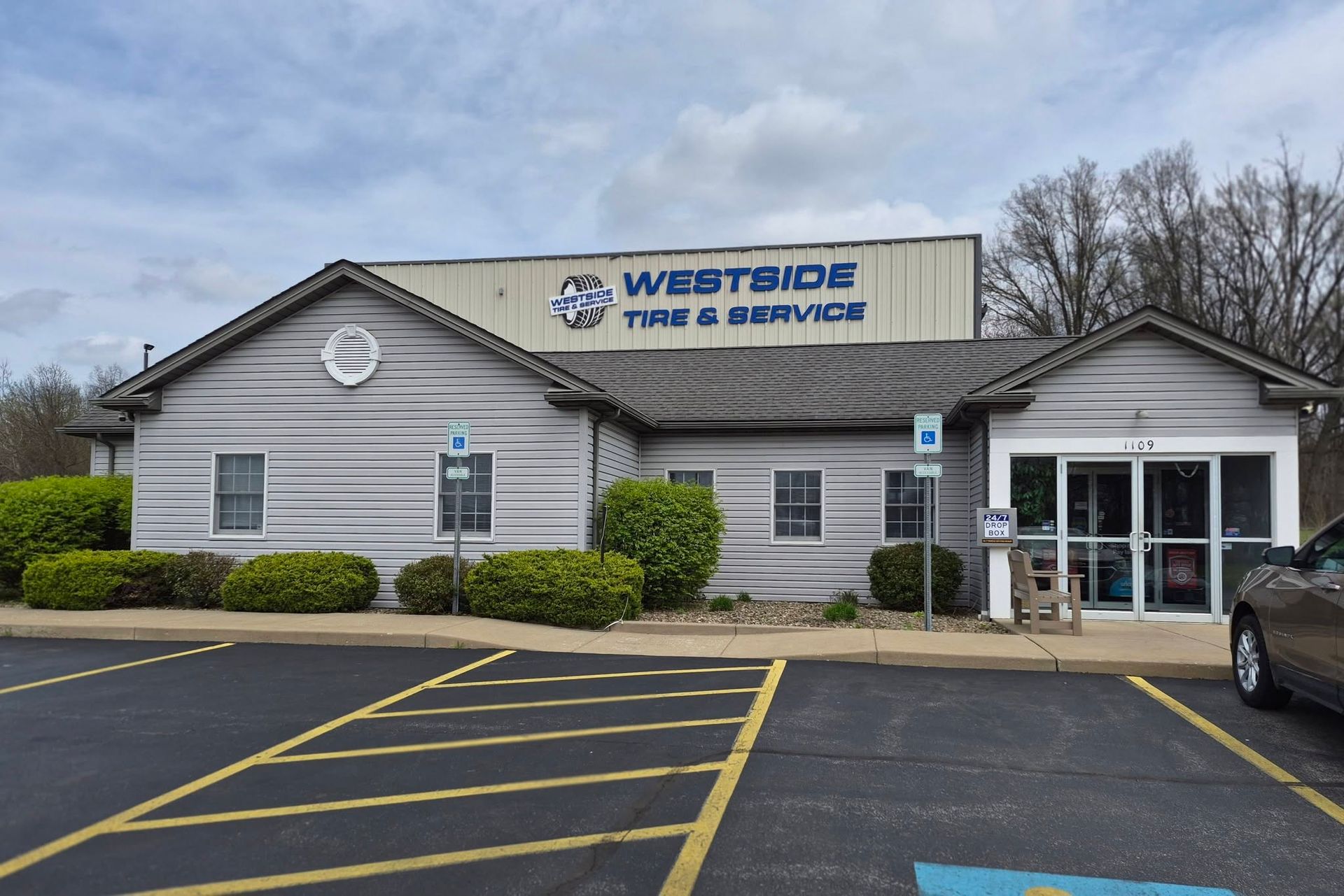 Storefront with gray siding and yellow parking lines | Westside Tire & Service