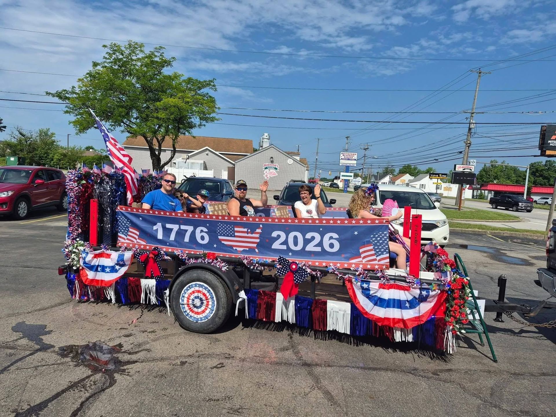Patriotic parade float with banners, red-white-blue bunting, and flags outdoors | Westside Tire & Service