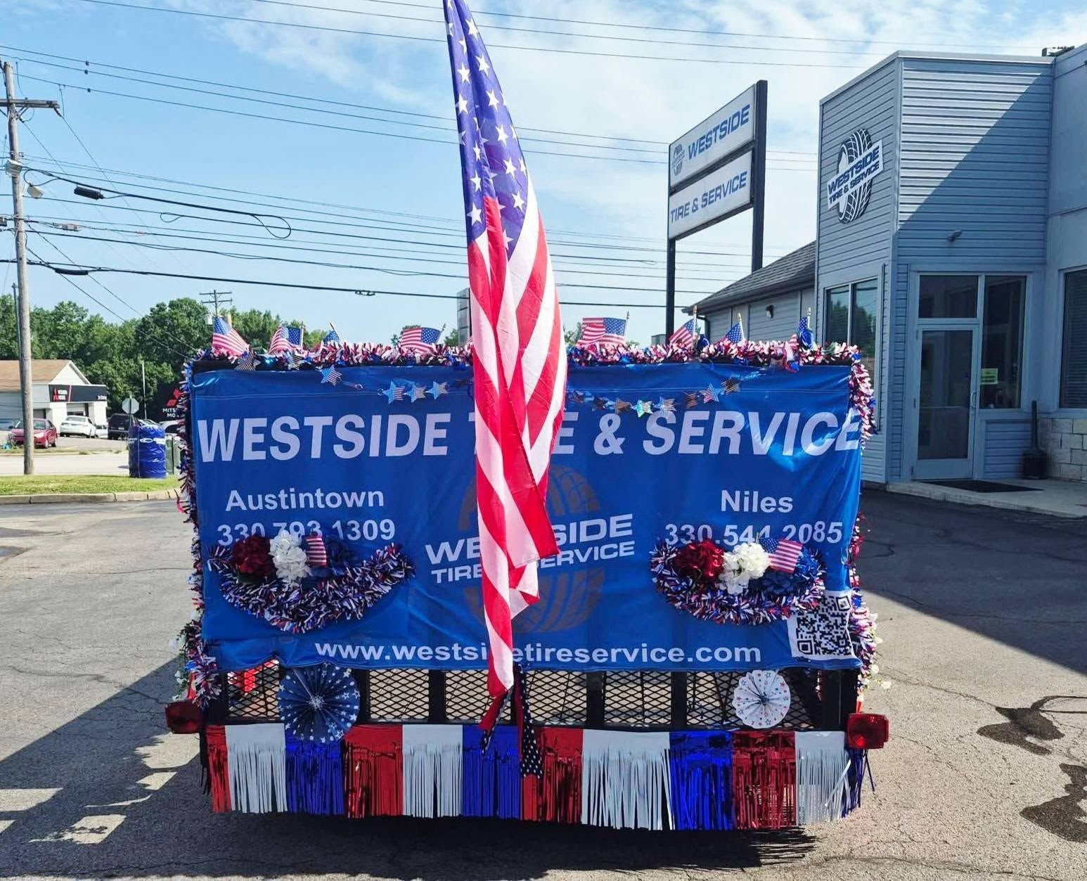 Patriotic float with decorations, and business sign in a parade | Westside Tire & Service