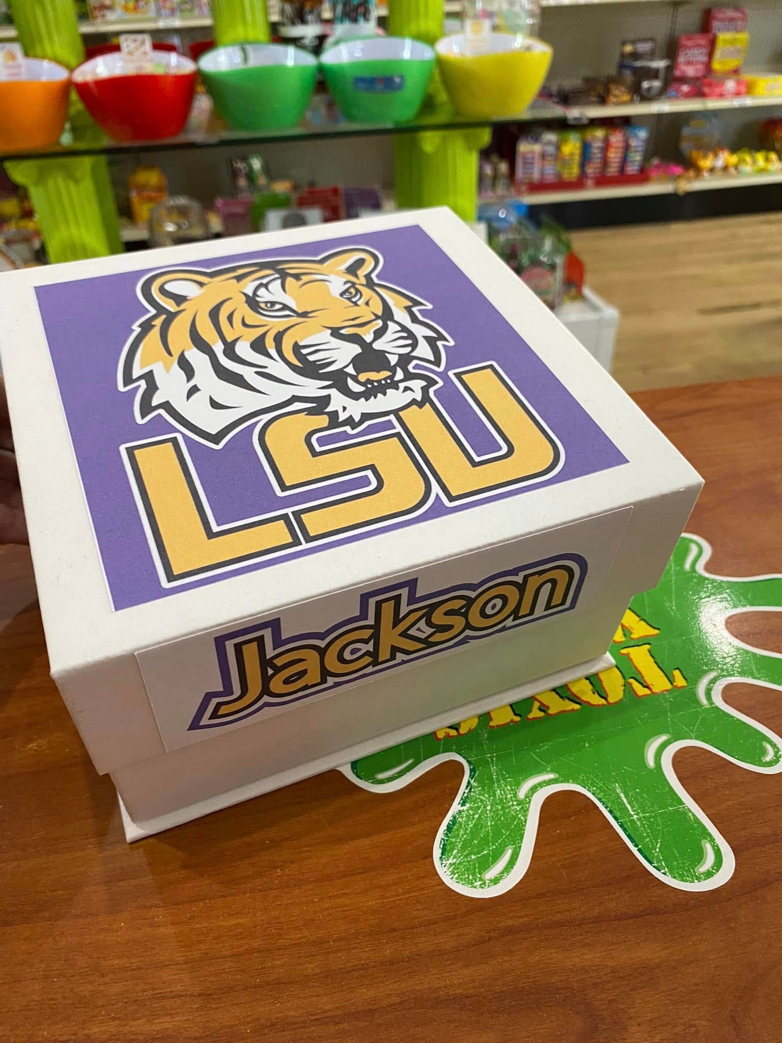 LSU tiger logo on a purple Jackson box sitting on a wooden table in a colorful store display