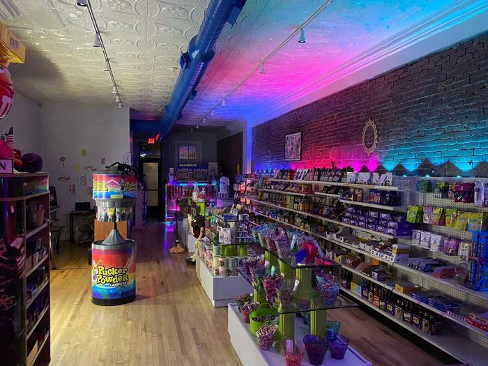 Colorful store aisle with shelves of merchandise and neon pink-blue lighting