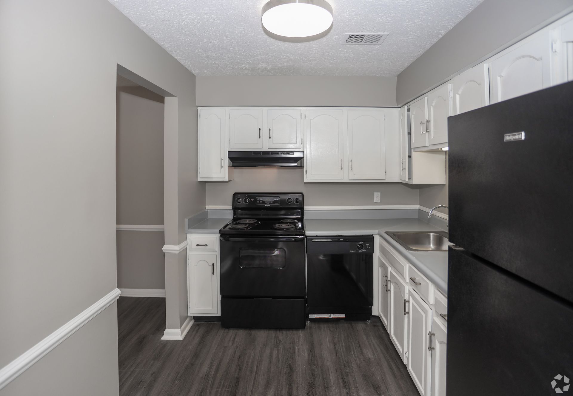 Kitchen with white cabinets, black appliances, gray walls and countertops.