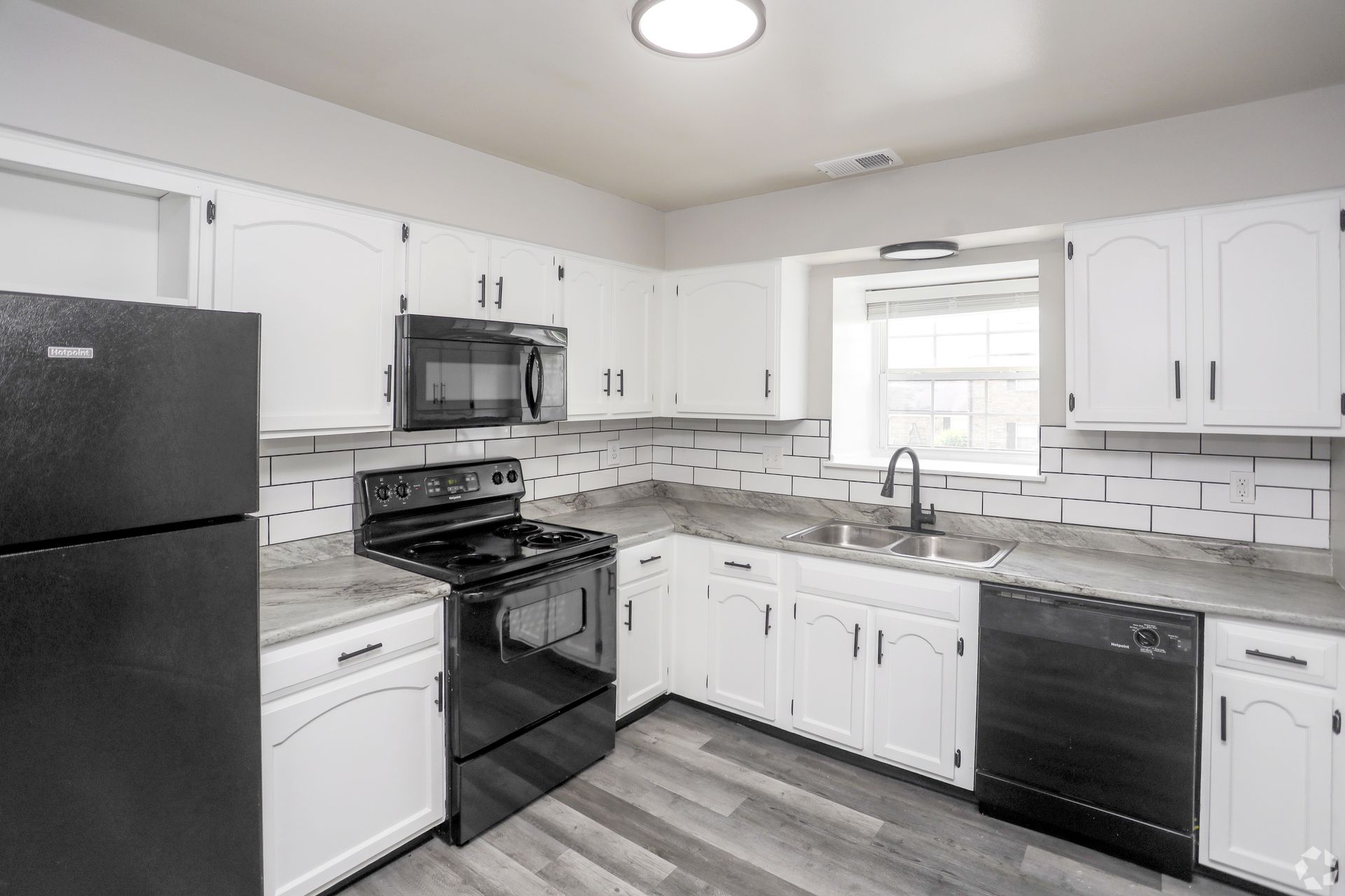 White kitchen with black appliances, including a refrigerator, oven, and dishwasher.