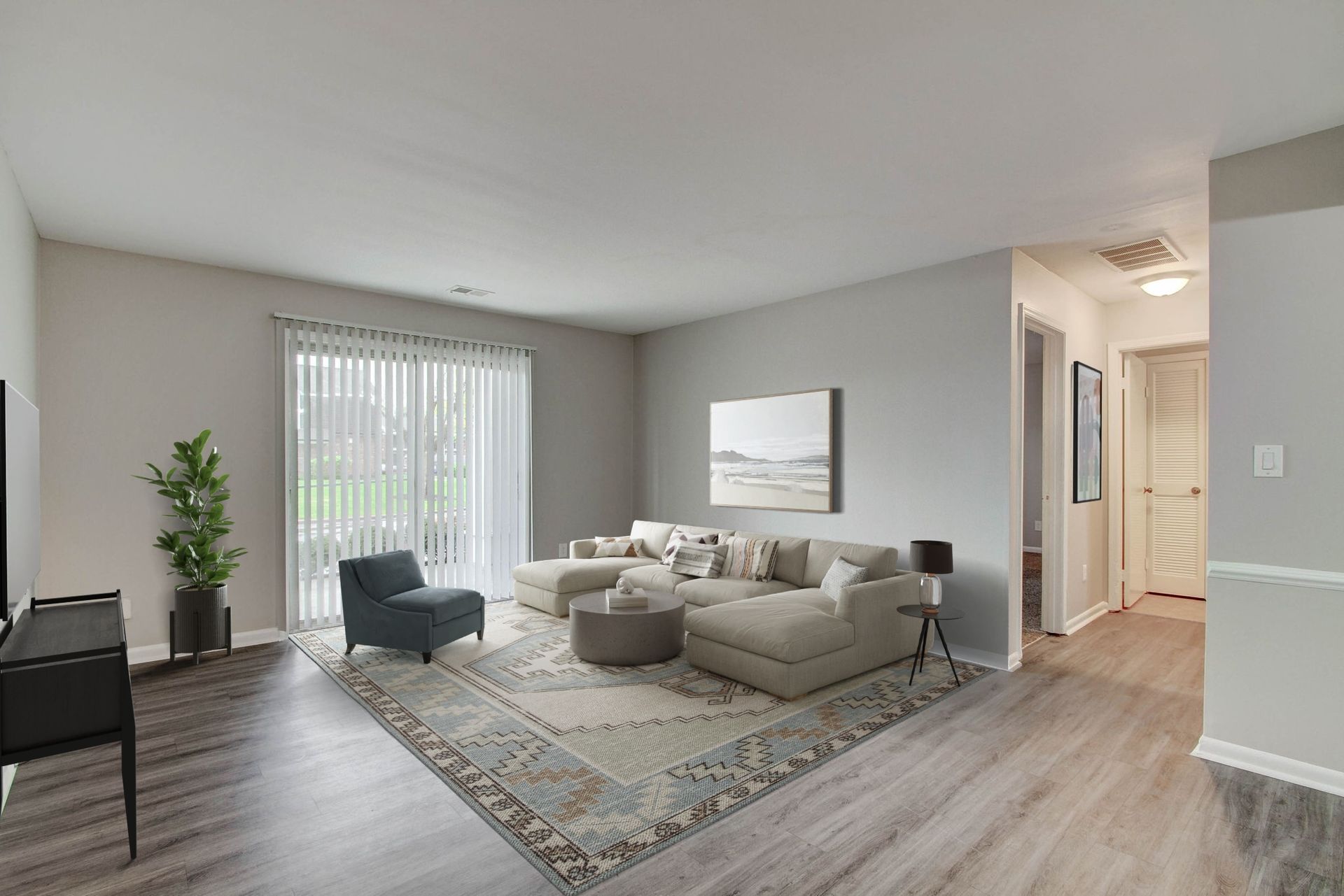 Spacious living room with sectional sofa, rug, and sliding glass door, bathed in natural light.