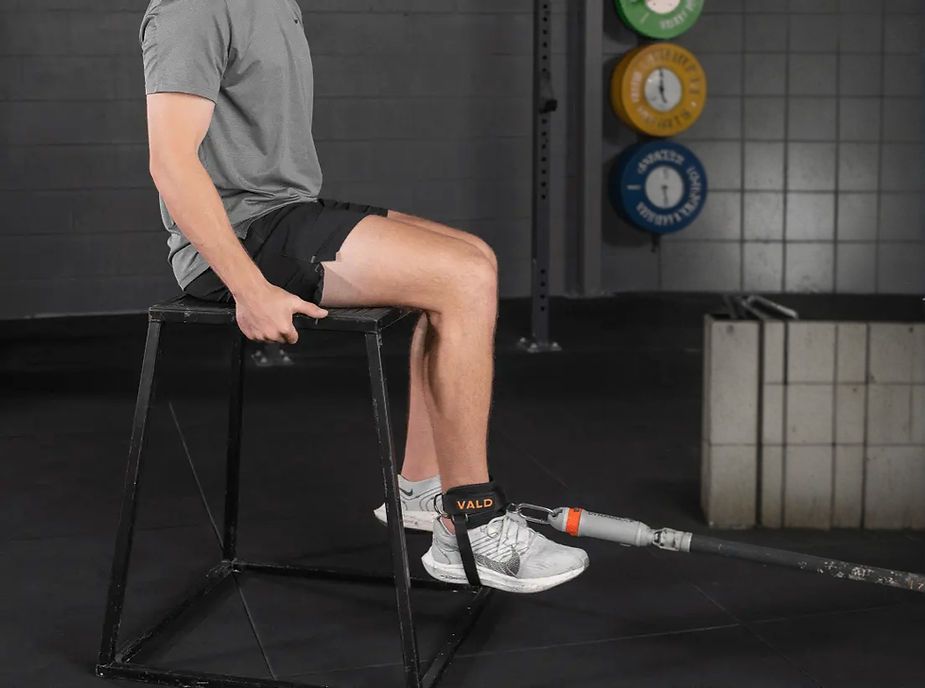 A man is sitting on a box with his legs crossed in a gym. A man is sitting on a box with his legs crossed in a gym.