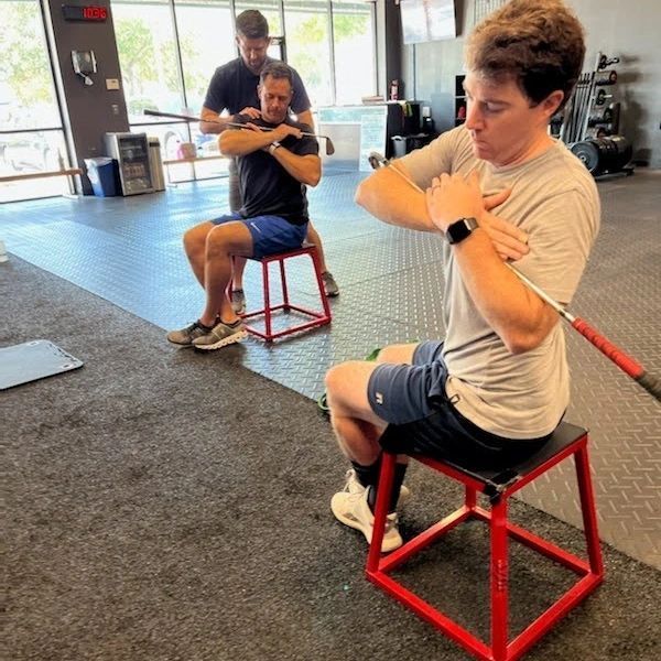 A man is helping a woman do exercises on a bench in a gym. A man is helping a woman do exercises on a bench in a gym.