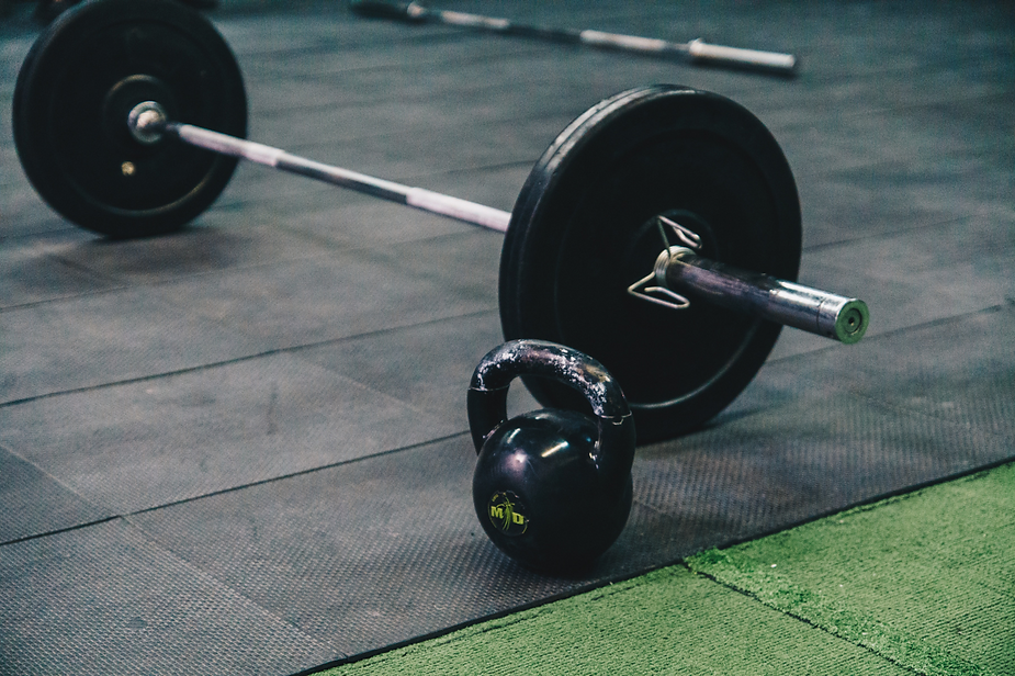 A barbell and a kettlebell are on the floor in a gym. A barbell and a kettlebell are on the floor in a gym.