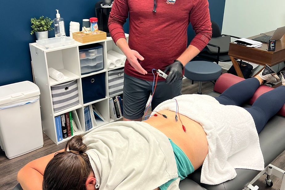 A man is standing next to a woman laying on a table. A man is standing next to a woman laying on a table.