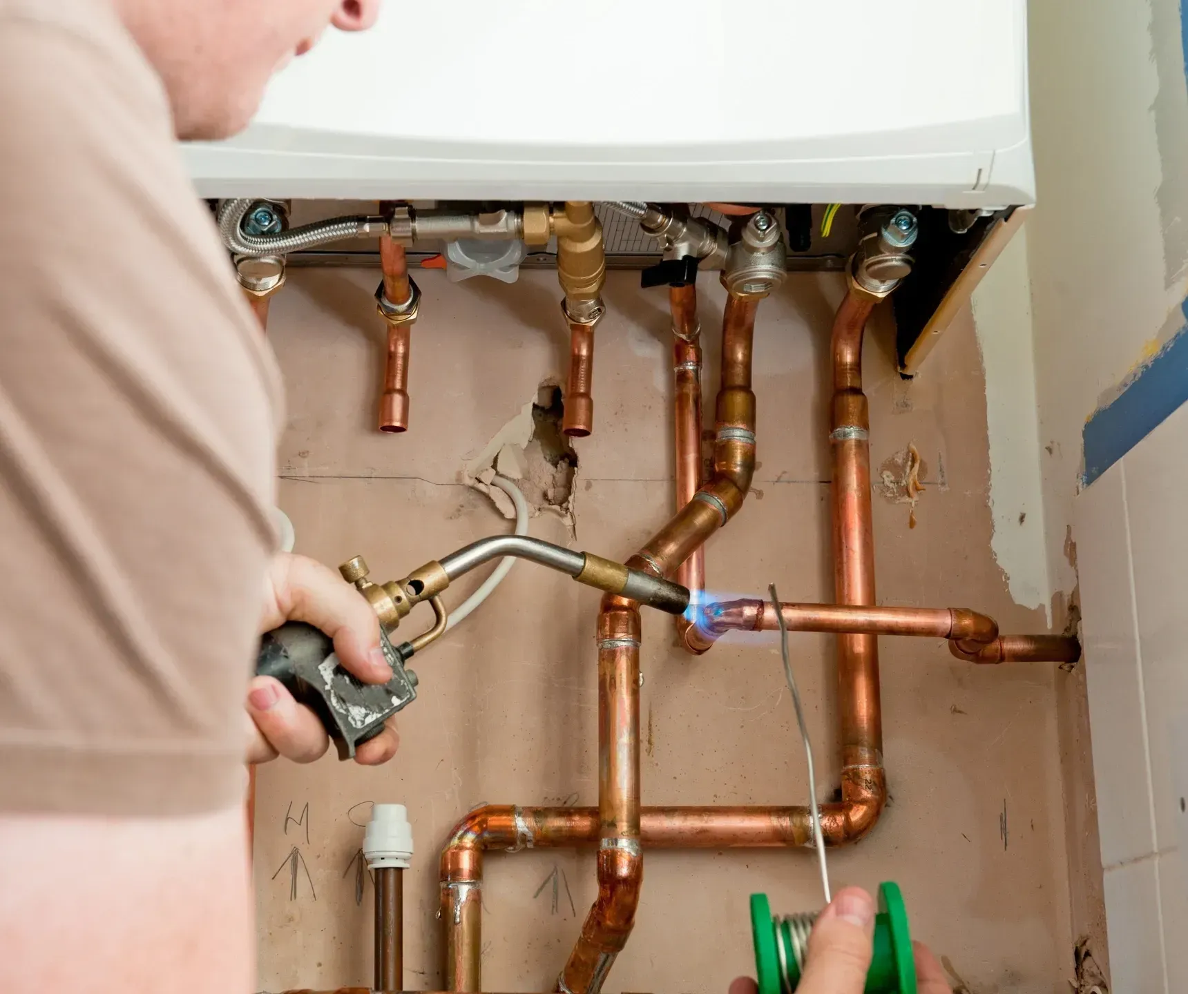 A man is welding copper pipes with a torch