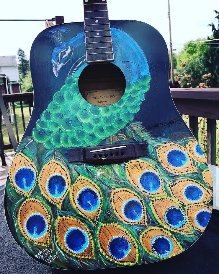 Decorated acoustic guitar with peacock-feather design in blue, green, and gold