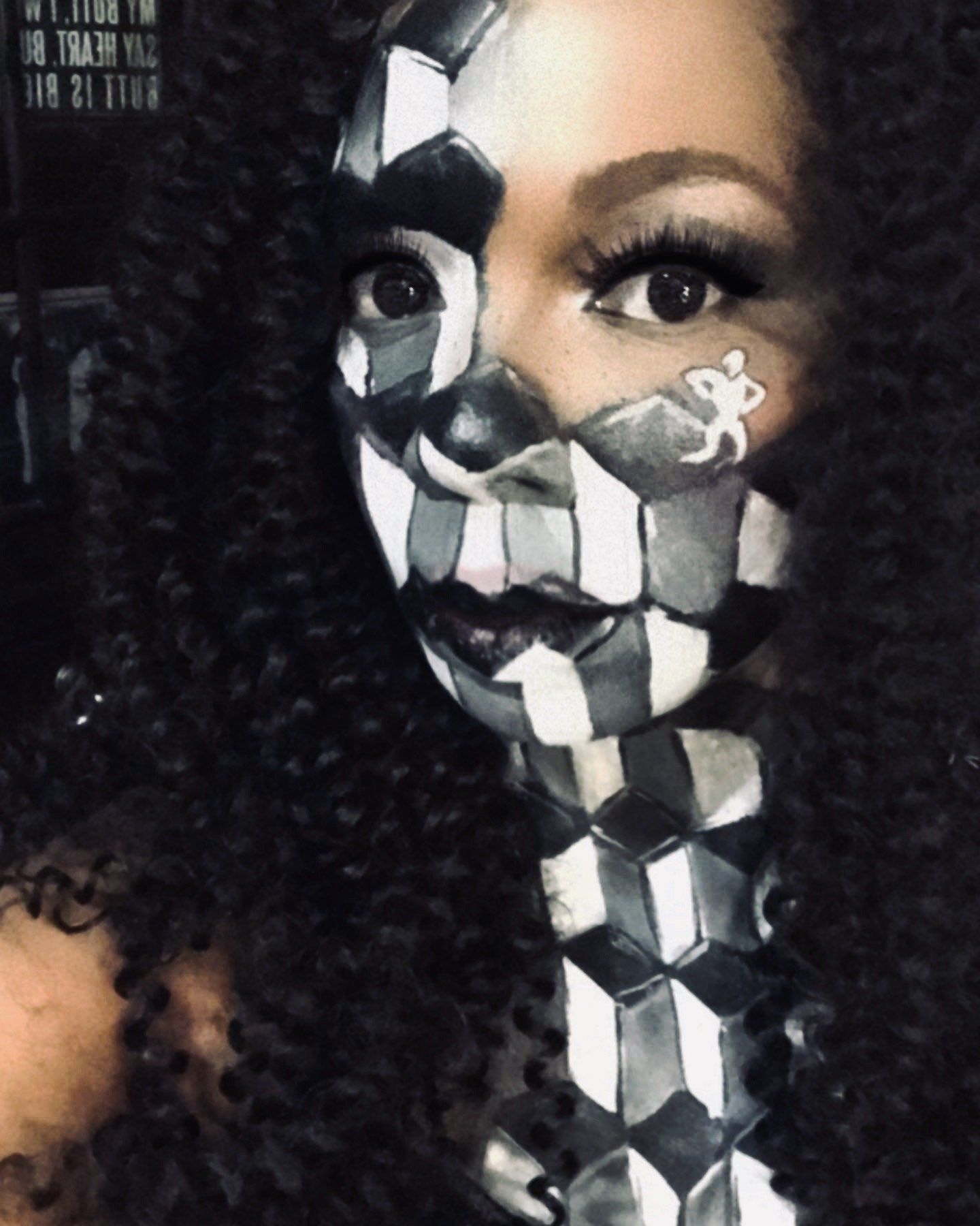 Close-up portrait with black-and-white geometric face paint and curly hair against a dark background