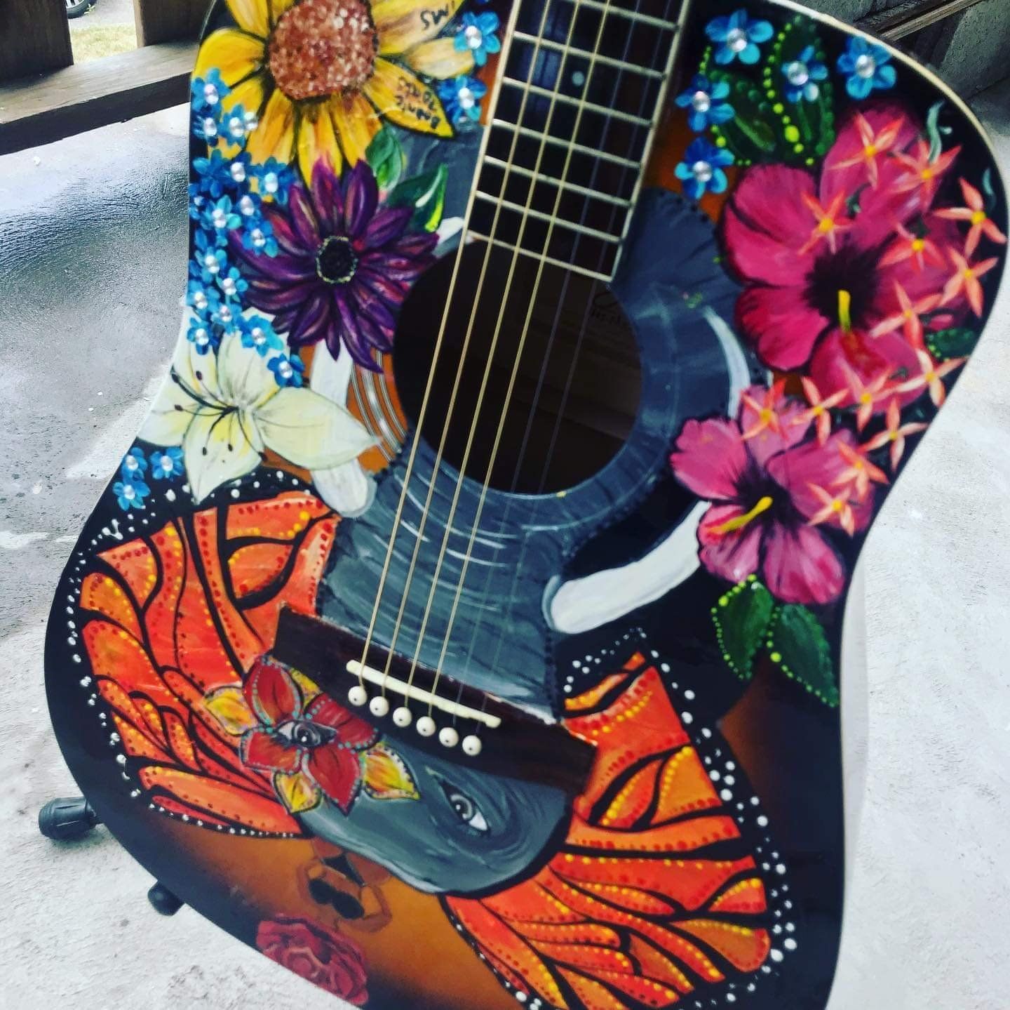 Colorful floral and butterfly-painted acoustic guitar with bright orange and purple accents