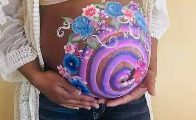 Pregnant belly with colorful rainbow and floral body paint design