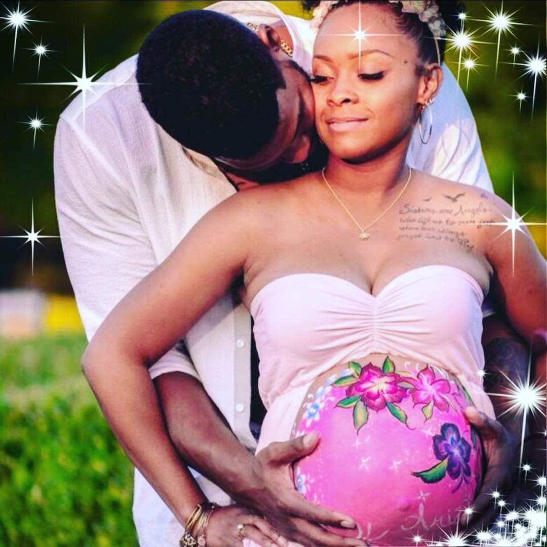 Couple embracing a pregnant woman outdoors, with sparkly overlay and pink floral maternity dress