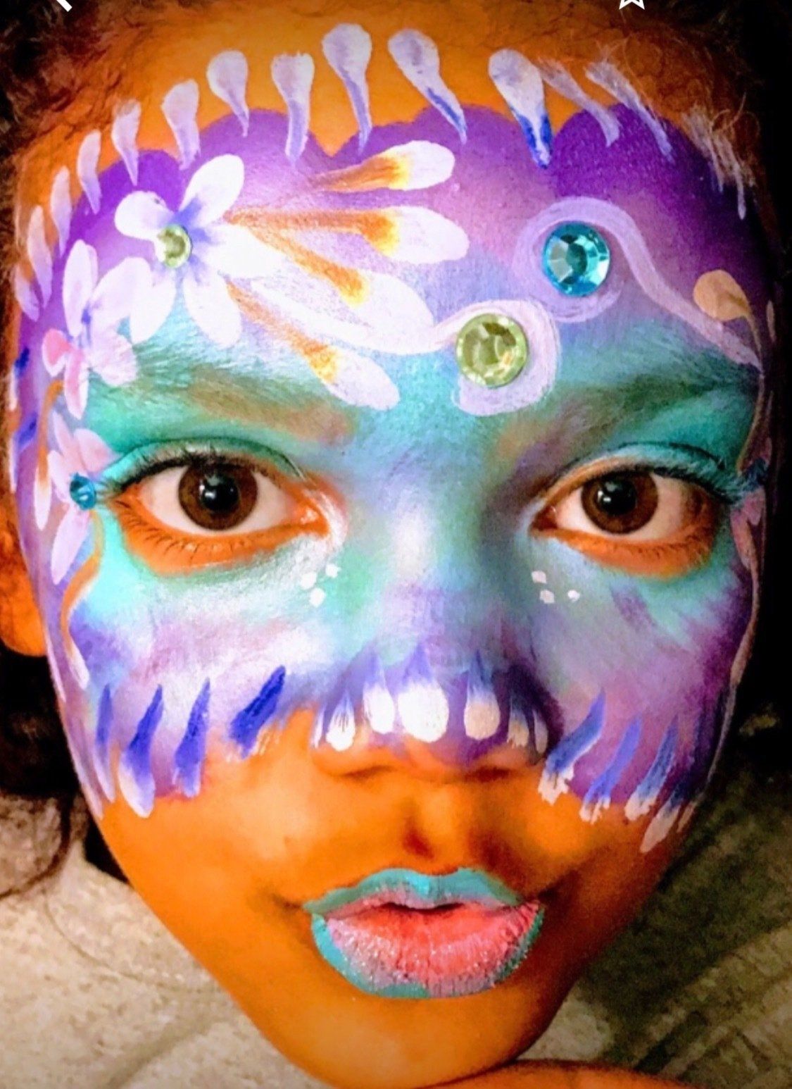 Colorful face paint with purple, blue, orange, and white floral designs on a person's face