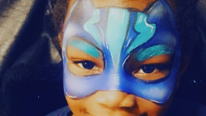 Close-up of a face with a blue and white painted mask design around the eyes and forehead