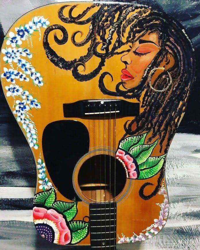 Decorated acoustic guitar with a painted face, flowers, and bold black-and-orange swirls