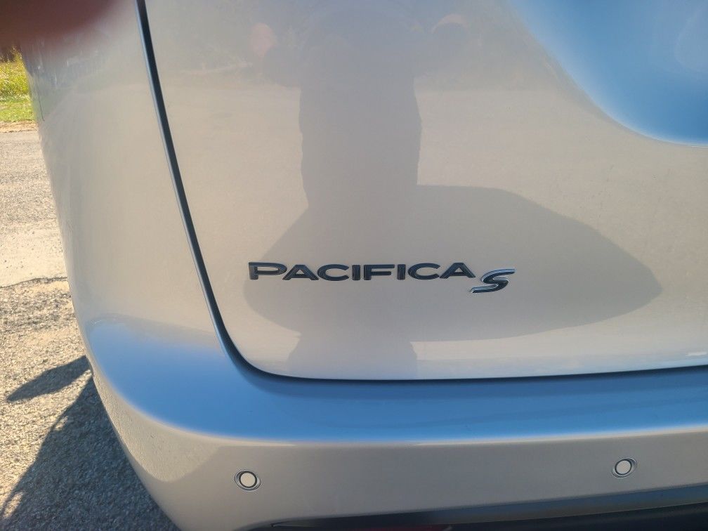 Rear of a white Chrysler Pacifica S, showing the model badge and bumper sensors.