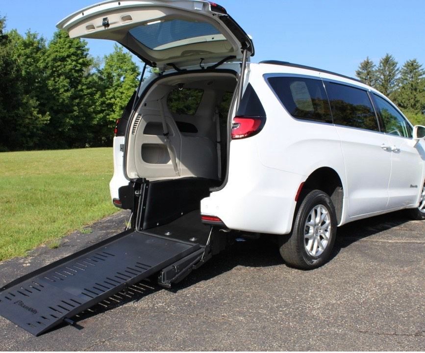 White SUV with rear hatch open and wheelchair ramp extended on a paved driveway