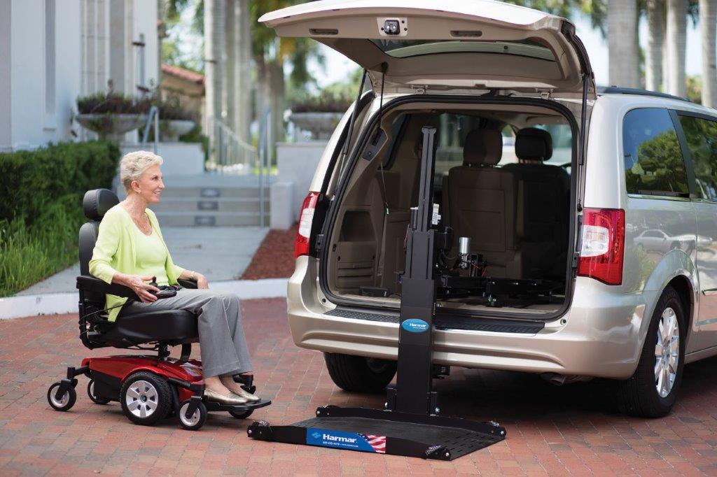 Woman in a power wheelchair using a van lift to load into an accessible vehicle on a driveway