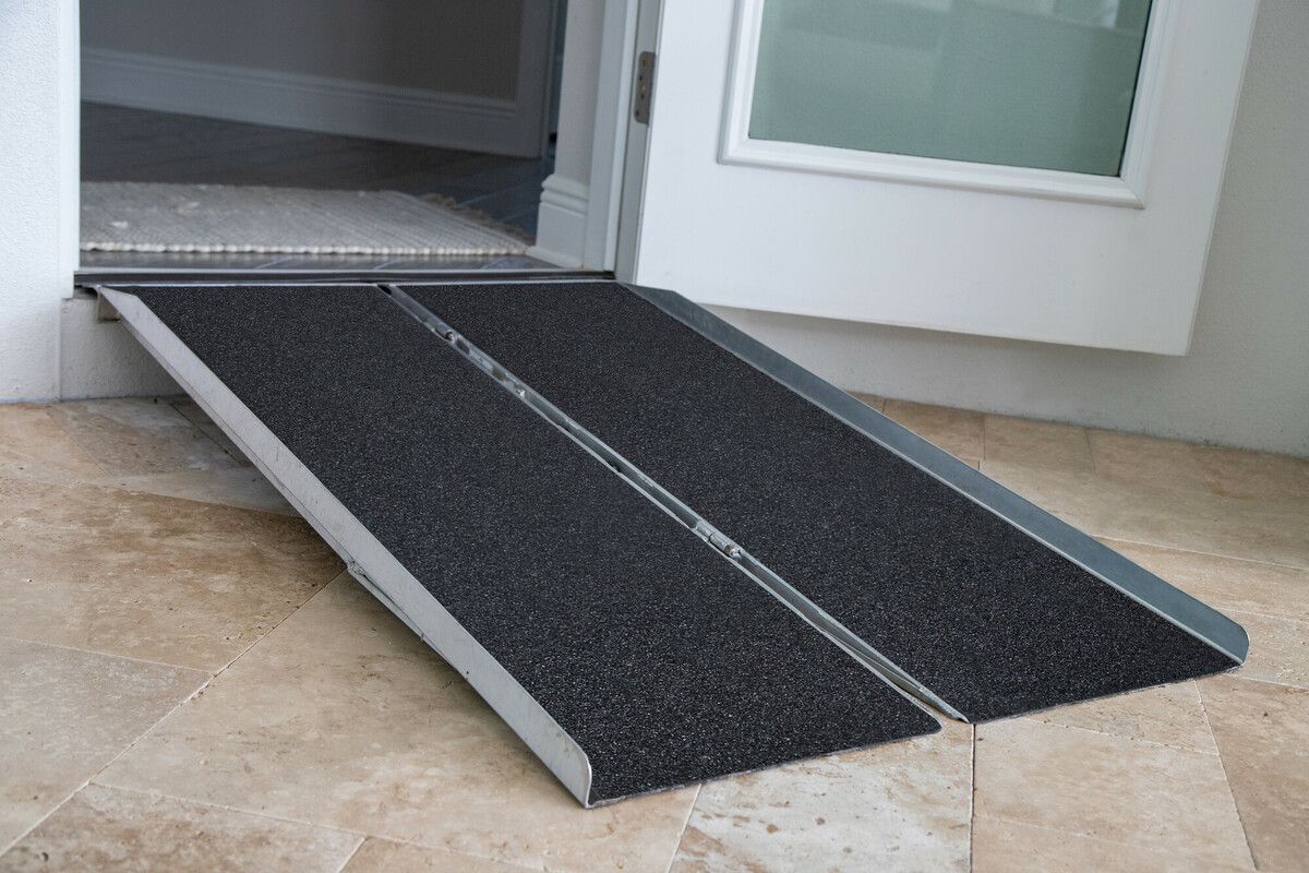 Black wheelchair ramp at a doorway over a tiled entrance floor