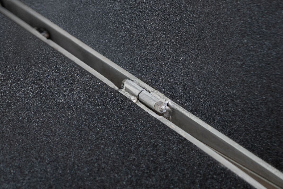 Close-up of a metal hinge on a textured dark gray surface