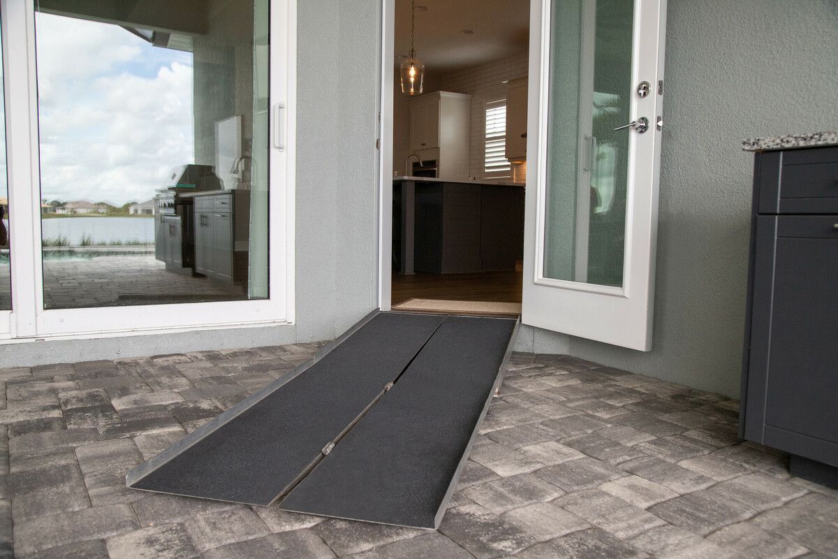 Open doorway with a black accessibility ramp leading into a building patio
