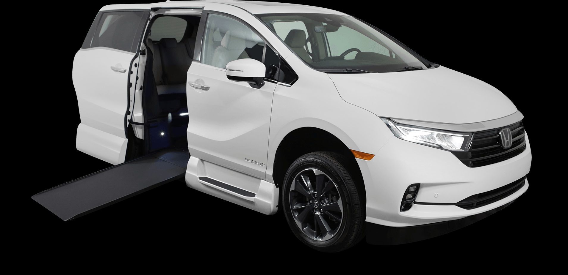 White minivan with side door open and wheelchair ramp extended.