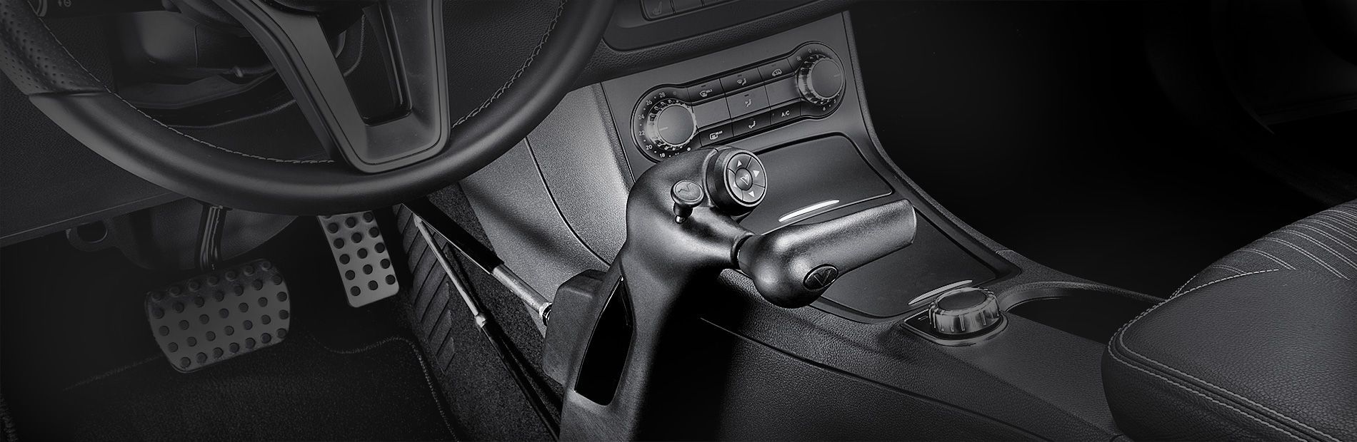 Car interior with steering wheel, pedals, center console, and black seats in a compact car.