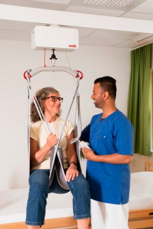Clinician assisting patient with a ceiling lift in a hospital room