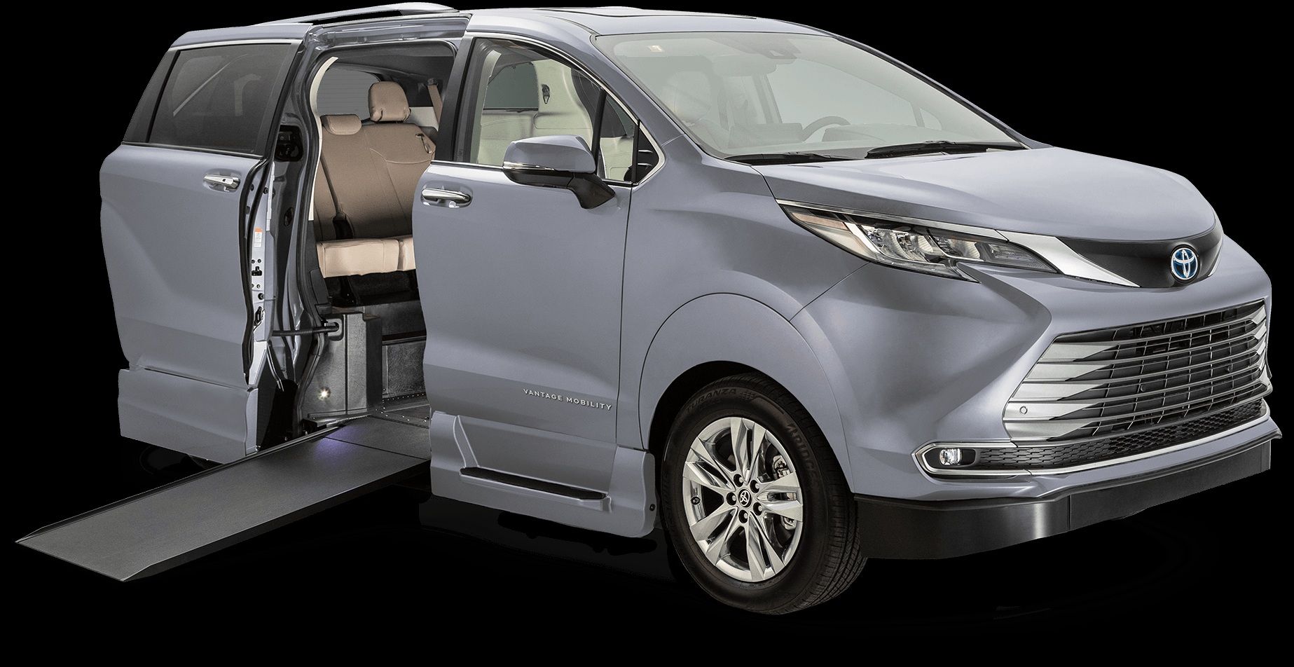 Gray minivan with side door open and wheelchair ramp extended, showing beige interior on a black background