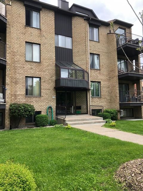 Un grand immeuble d’appartements en brique avec une pelouse verdoyante devant lui.