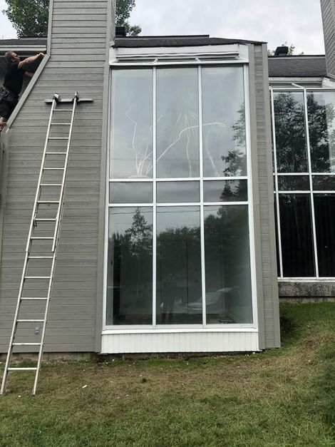 Un homme se tient debout sur le toit d’une maison avec une échelle.
