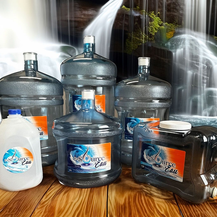 Plusieurs carafes et bouteilles d'eau sur une table en bois avec une cascade en arrière-plan