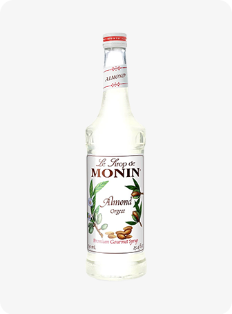 Bouteille de sirop d'amande Monin blanche avec étiquette florale sur fond uni