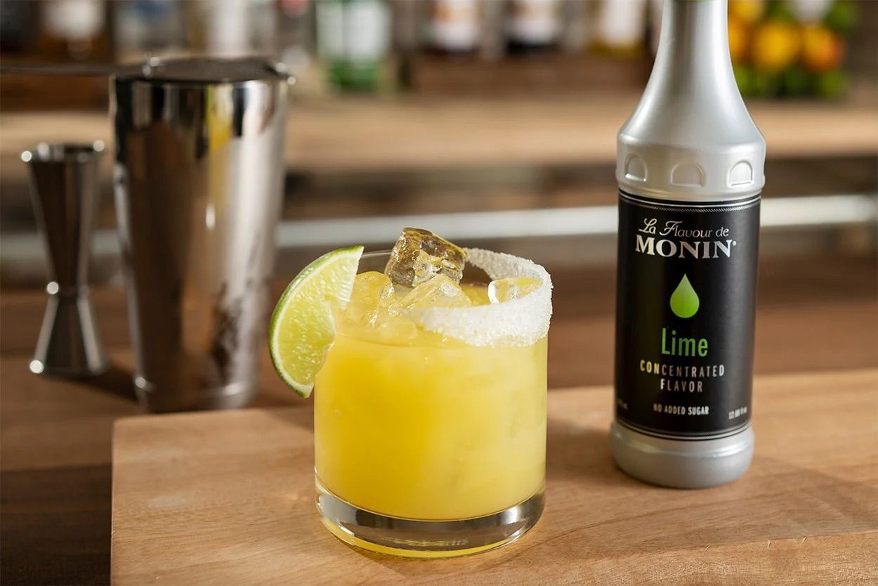 Bouteille de sirop de citron vert Monin avec bouchon noir sur fond blanc