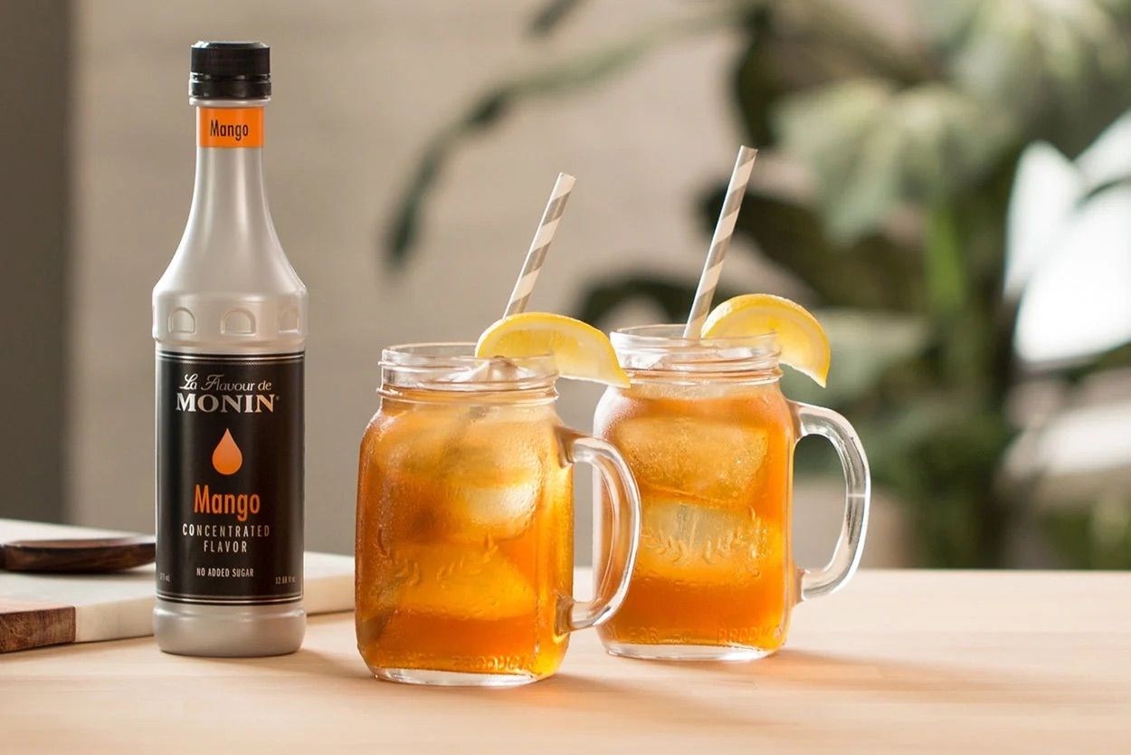 Bouteille de sirop de mangue Monin avec bouchon noir et étiquette orange sur fond blanc