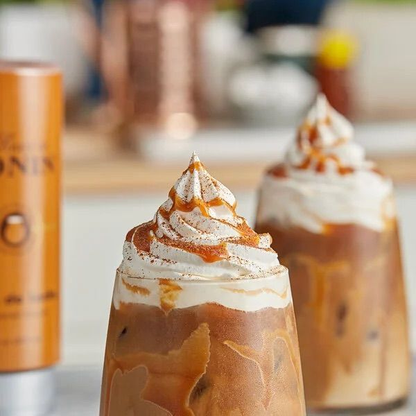 Bouteille de sirop Monin Dulce de Leche avec étiquette brune et bouchon argenté sur fond blanc
