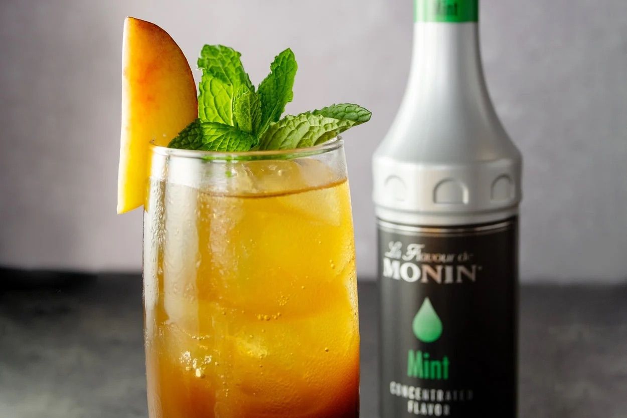 Bouteille de sirop de menthe Monin avec une étiquette noire et une touche de vert sur fond blanc