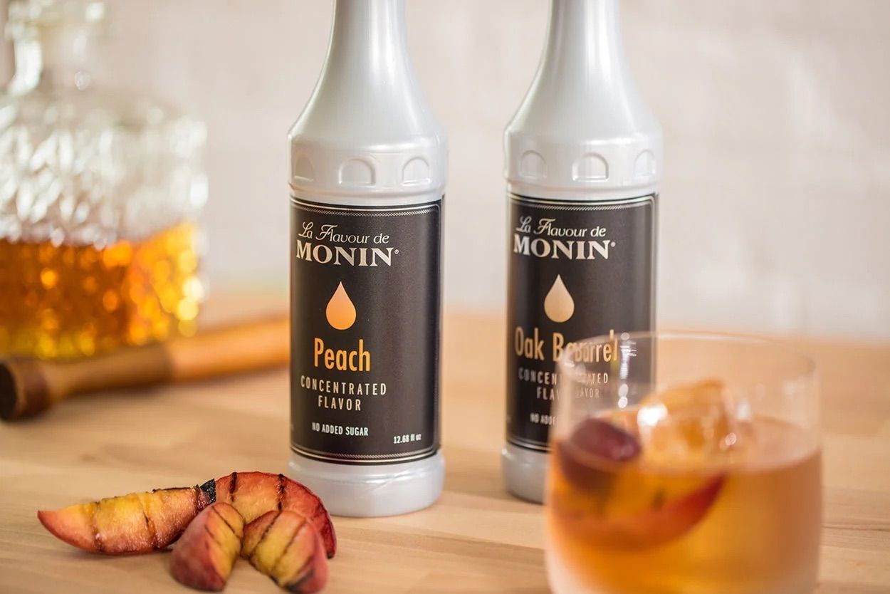 Bouteille de sirop à saveur de pêche MONIN avec étiquette noire et détails dorés