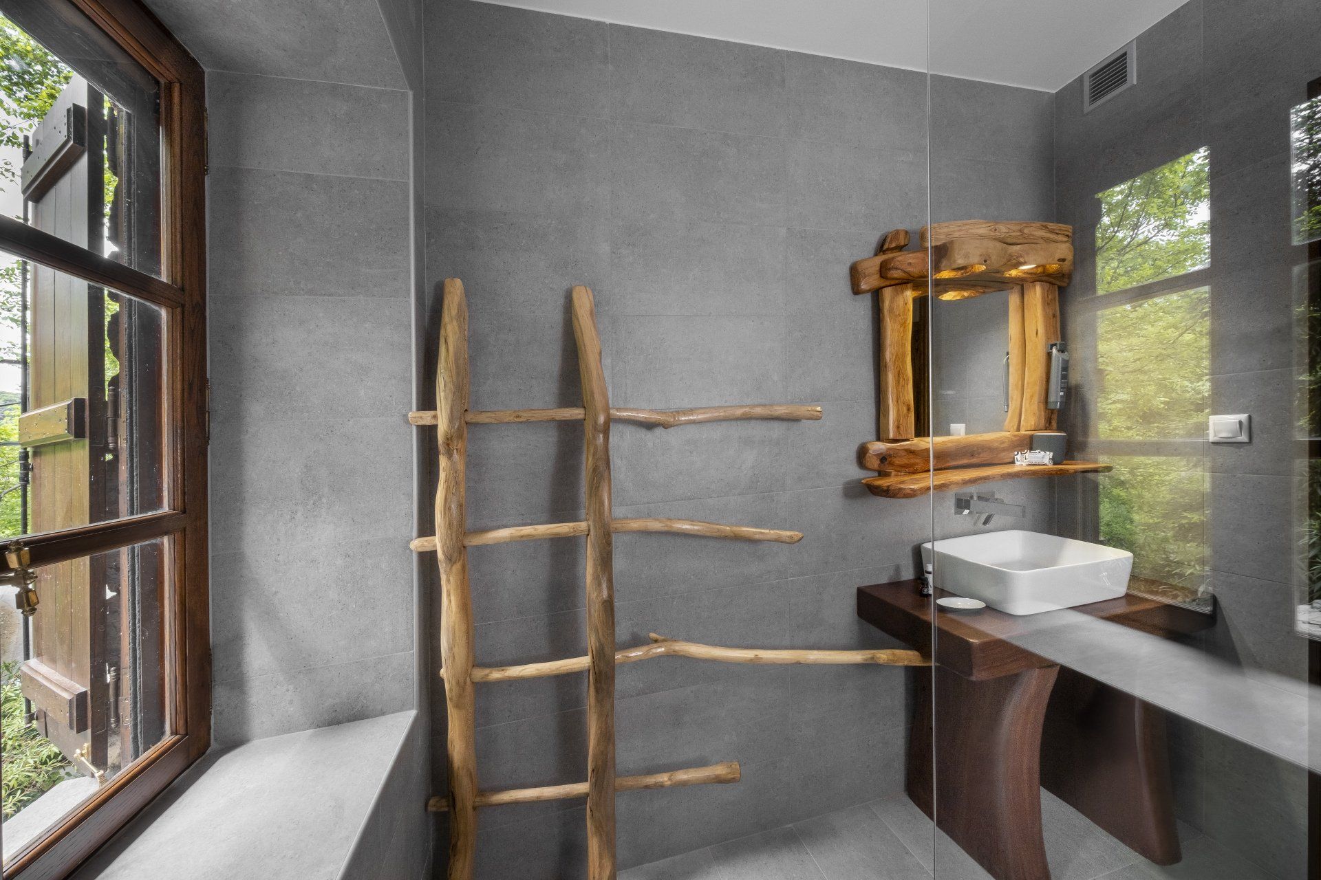 Bathroom with gray walls, wooden ladder, rustic mirror, and a white sink.