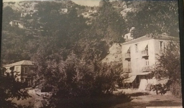 Two-story buildings nestled among trees on a hillside. Vintage sepia tone photo.