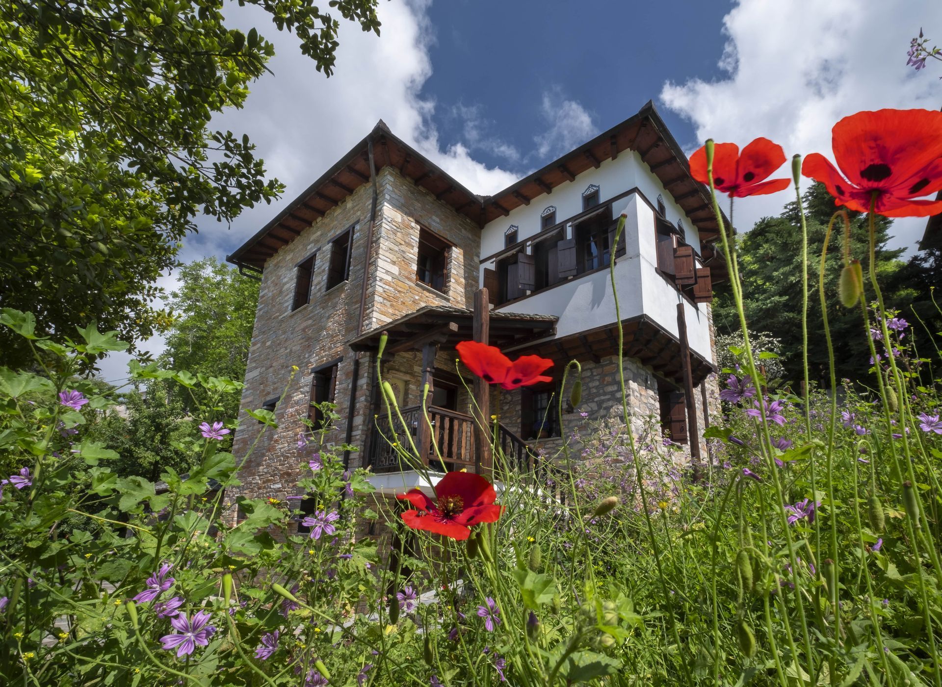 Stone house with white walls and red poppy flowers.